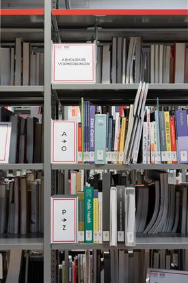 Foto: Nahaufnahme Vormerkregal mit mehreren Büchern. Schild: Abholbare Vormerkungen + A-O + P-Z.